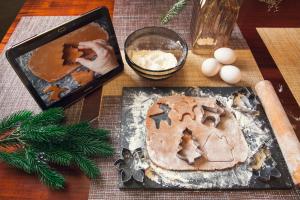 Baking station with cookie dough and cutters, rolling pin, eggs, flour and a tablet showing the recipe