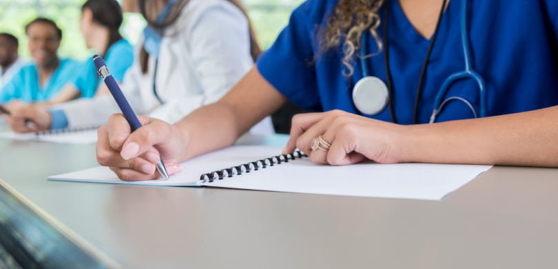 Woman in scrubs writing in notebook
