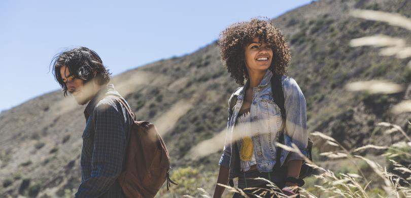 Two young adults hiking with hill in background