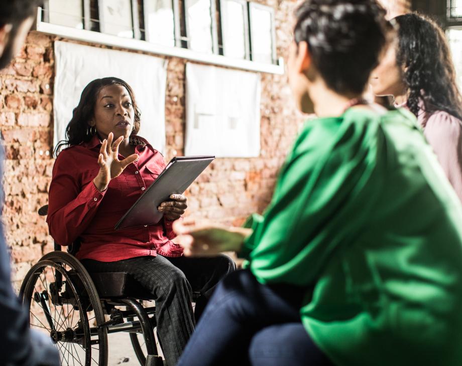 Businesswoman in wheelchair leading group discussion in creative office
