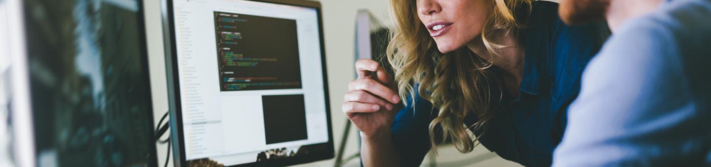 Two people looking at two computer screens